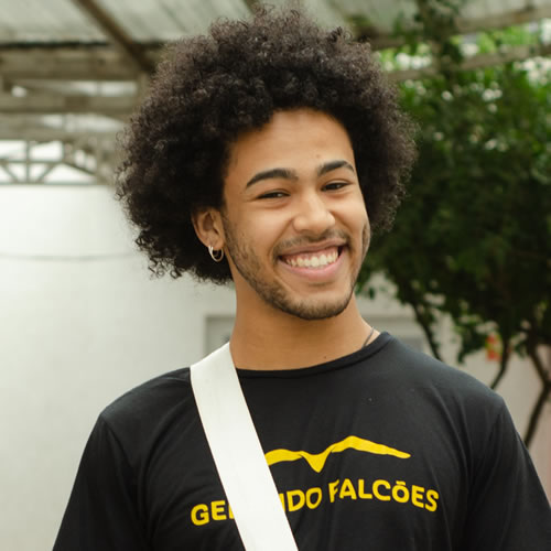 Foto de Welber Simões - Instrutor de percussão sorrindo para câmera com uma camiseta da gerando falcões e um black power